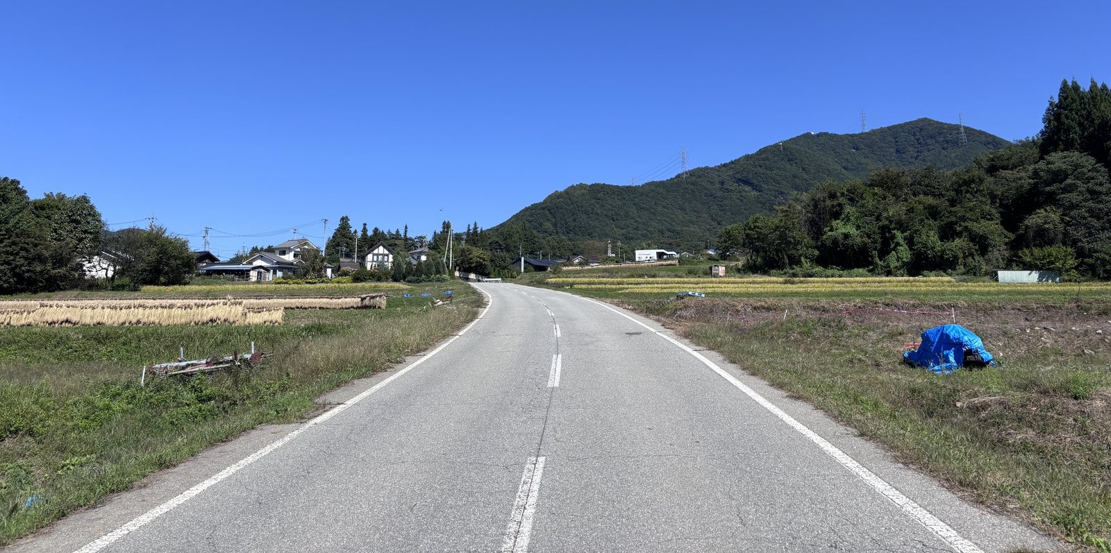 田んぼの中を、山のふもとの集落へ続く道